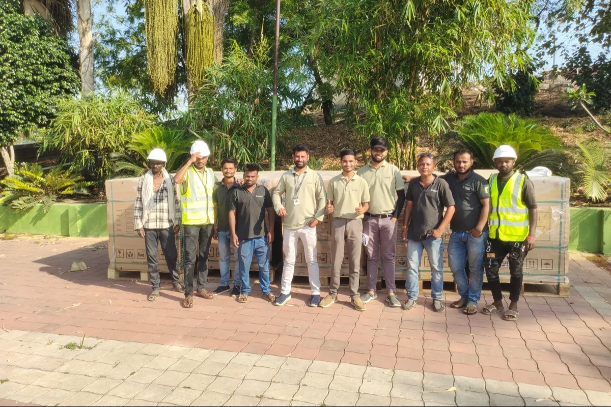 Nine members of the installation team standing in front of the module crates